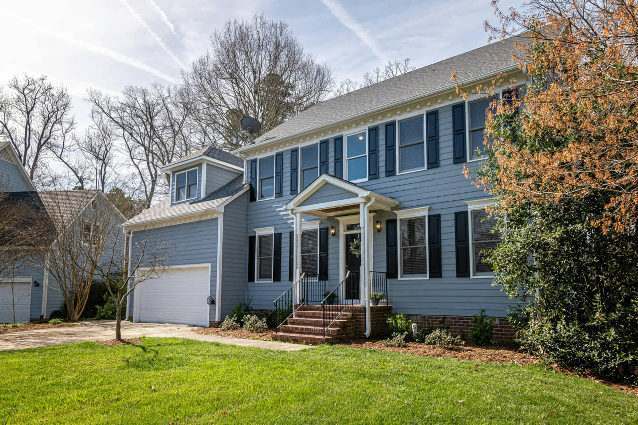 Exterior of a home with horizontal blue paneling and many windows.