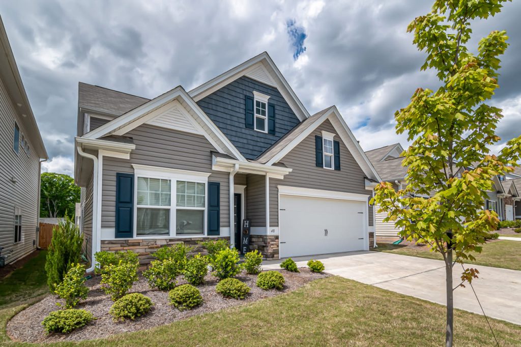 Exterior of a blue and grey home with white trim in a suburban neighborhood.